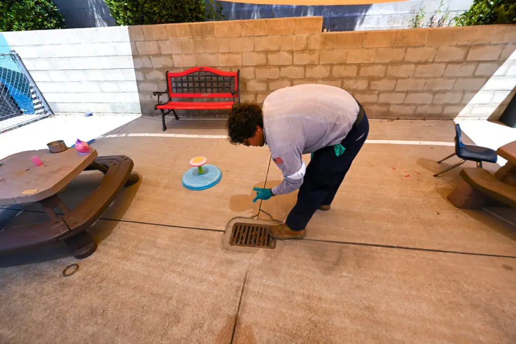 Vector Control Inspector Kevin Isunza looks for mosquitoes in drain...