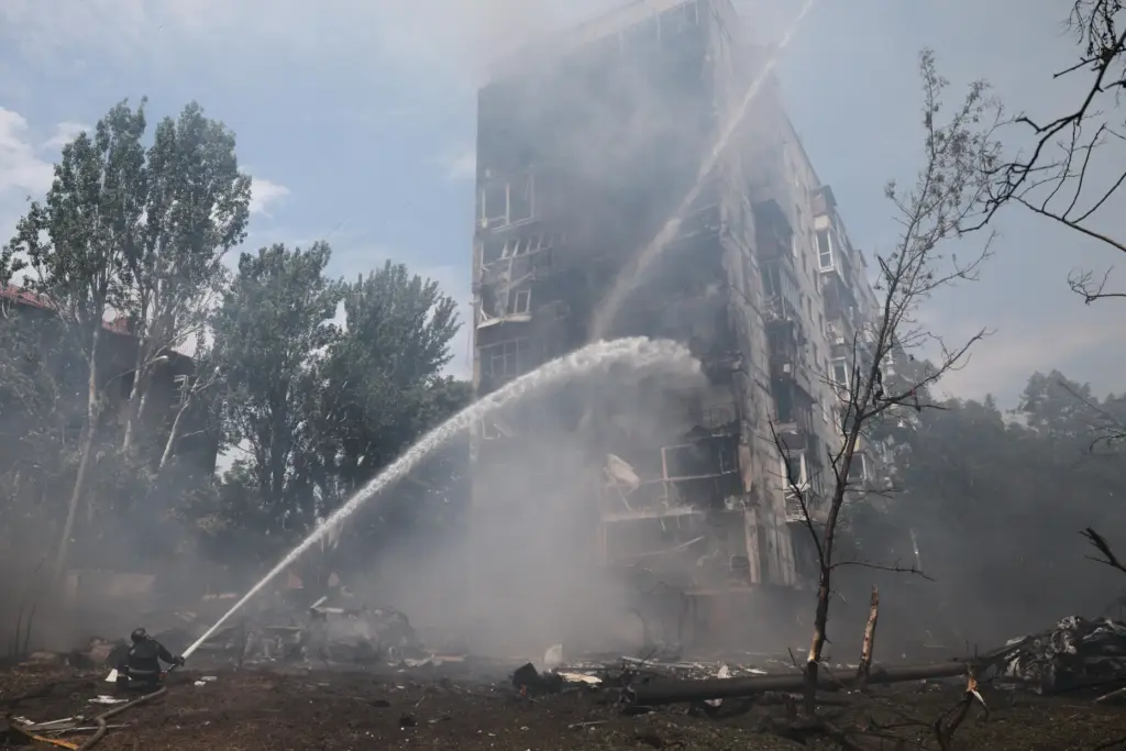 Rescue workers try to put out a fire of a...
