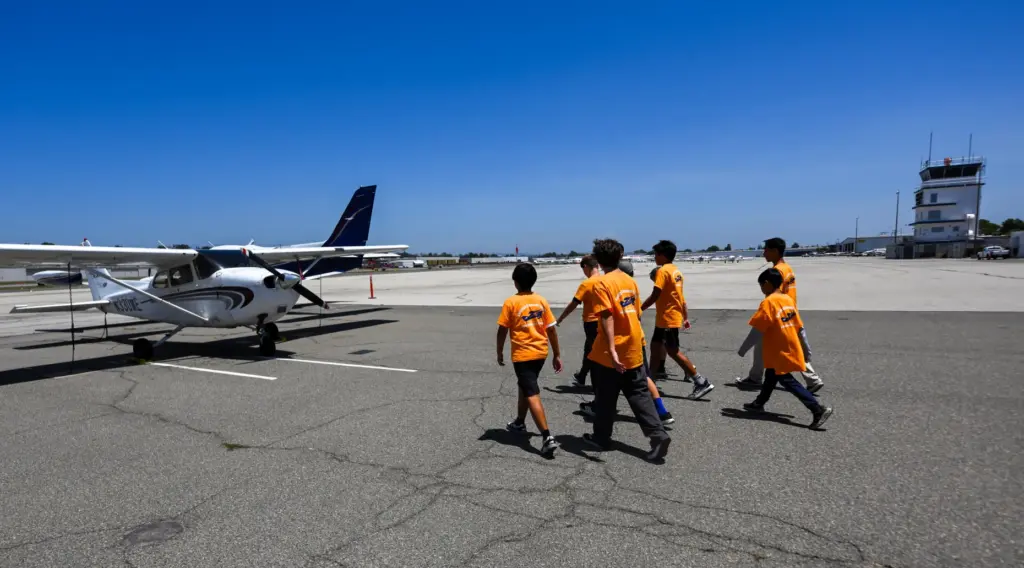 Counselor Baominh Dang leads campers to a Cessna 172 during...