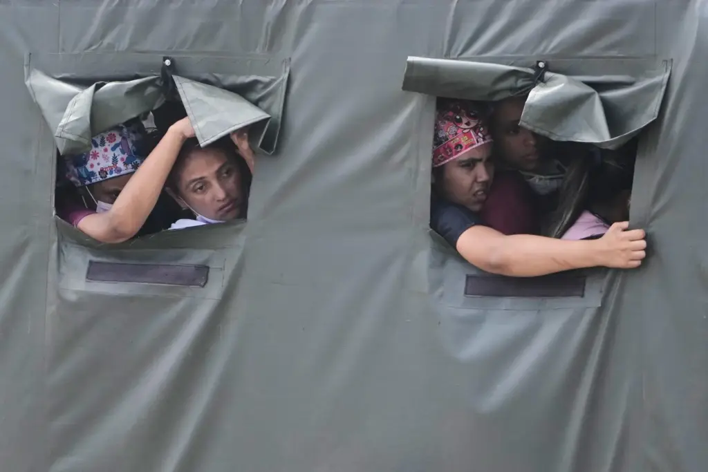 FILE – Health workers ride in a truck on their...