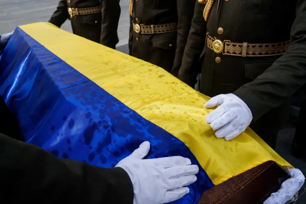 An honor guard straightens out the flag draped over the...