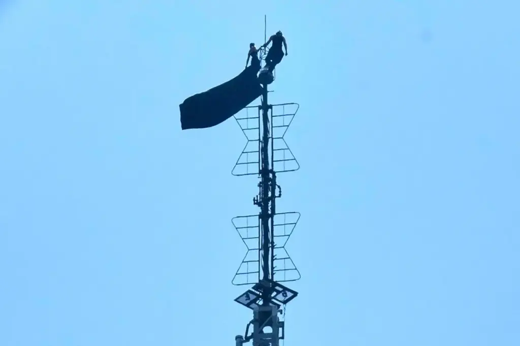Two people stand on the tip of the antenna of...