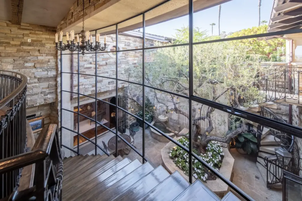 The gently curving staircase descends alongside a massive grid-style window...