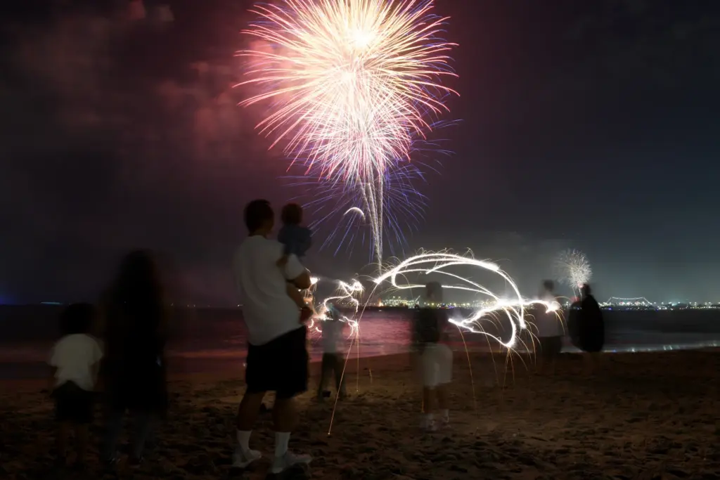 Children play with sparklers as simultaneous fireworks displays in Long...