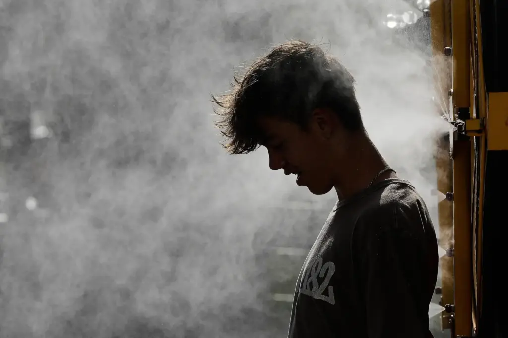 Holden Newcomb, 14, cools off in a mister.