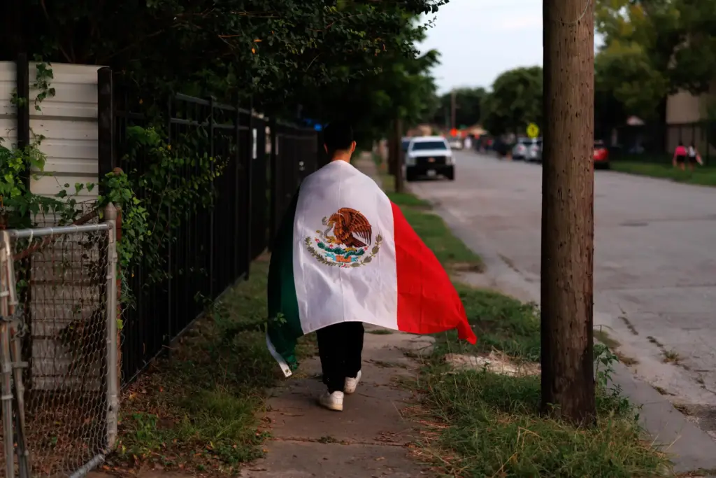 A man walks home draped in a Mexican flag after...
