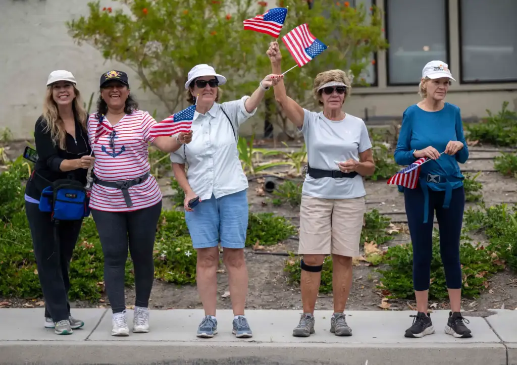 Parade-goers wave American flags as they watch the city of...