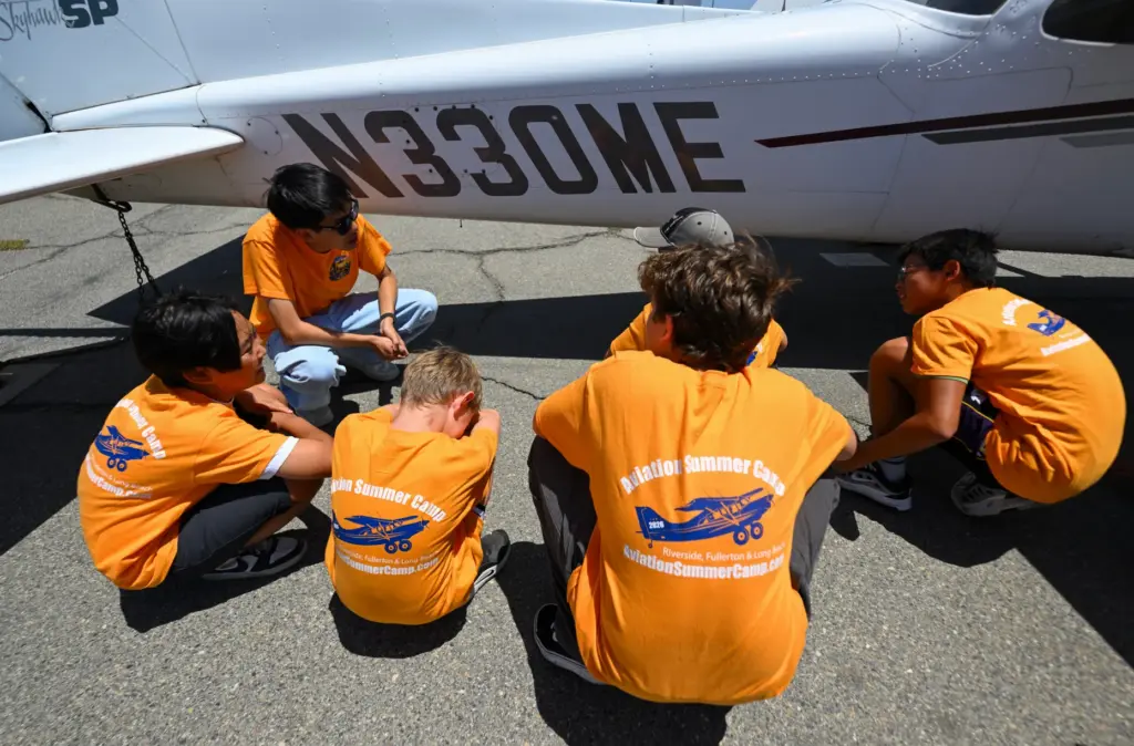 Counselor Baominh Dang shows campers how to preflight an Cessna...