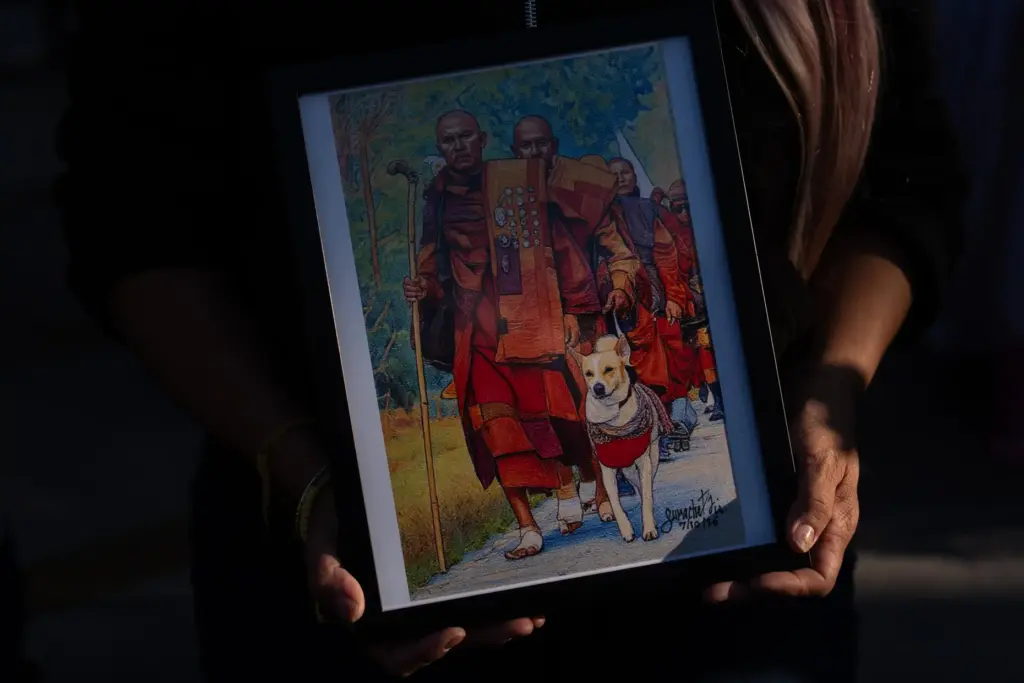 An attendee holds a framed painting depicting Bhikkhu Pannakara, a...