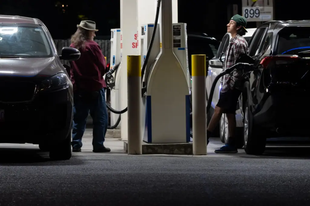 FILE – People fill up fuel tanks at a gas...