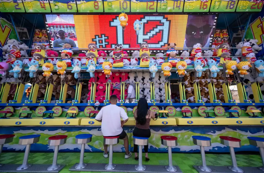 Fairgoers shoot water at targets as they play a water...