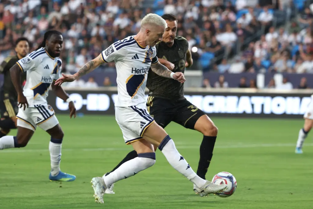 Galaxy midfielder Marco Reus, front, takes a shot while defended...