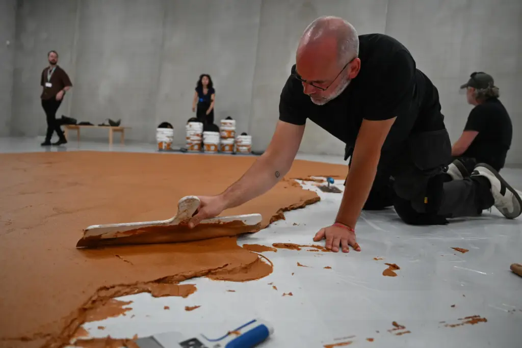 Workers spread peanut butter on a floor to re-create the 