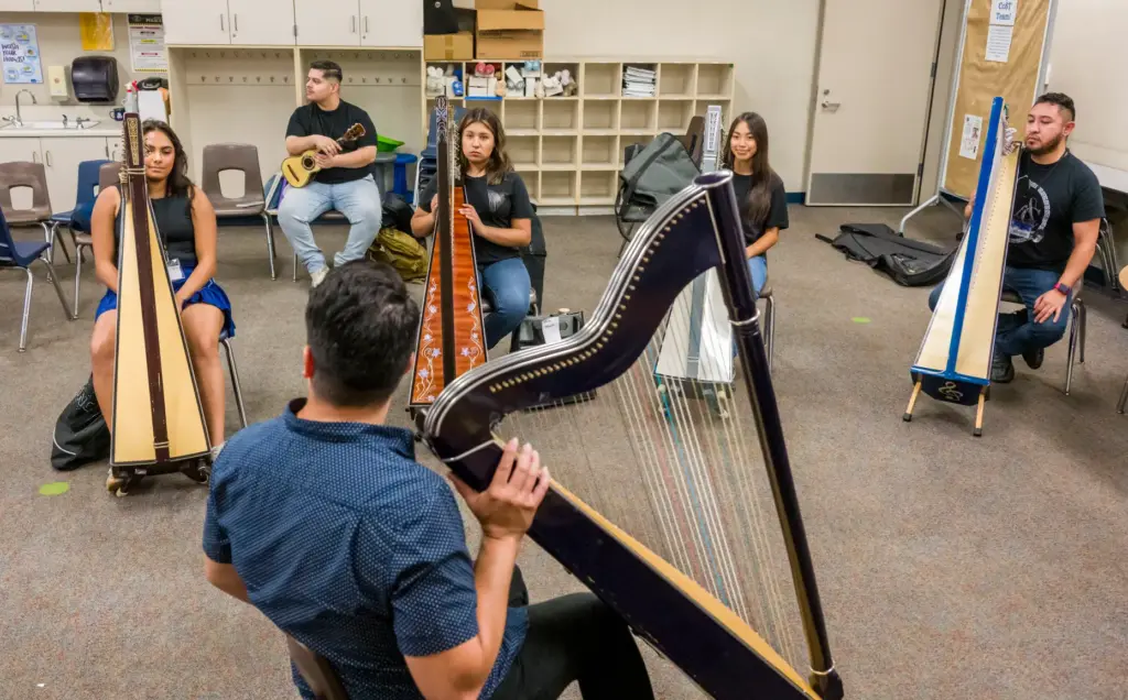 Harp instructor Guillermo AcuÃ±a, bottom, works with his students during...