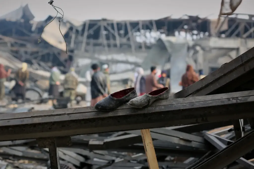 FILE – Residents and rescue workers inspect the site of...