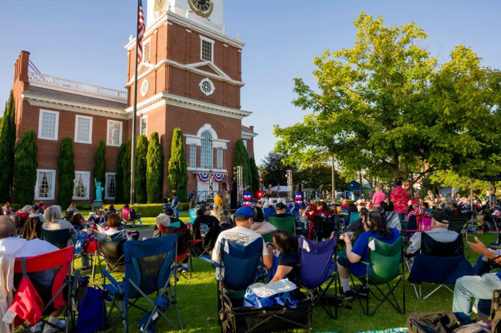 Families setup chairs and blankets on the lawn during the...