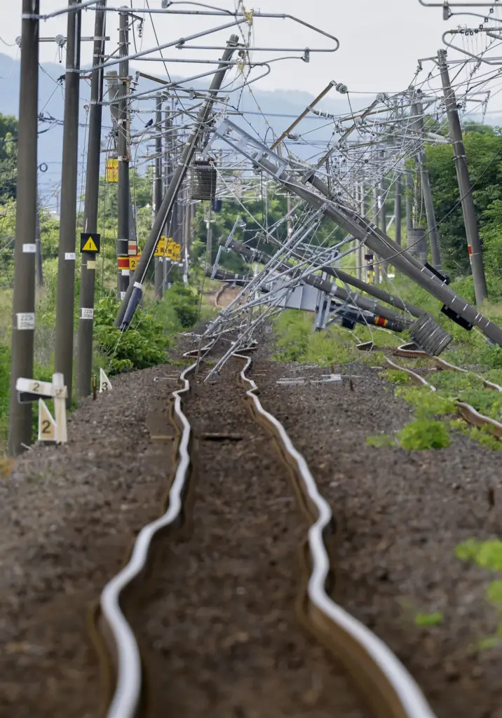 A warped railway track and fallen utility poles between Ogawa and Arisa stations