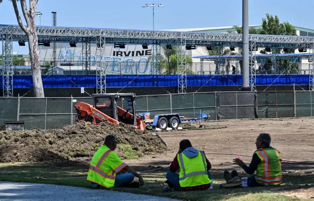 Workers take a break from clearing an area that will...