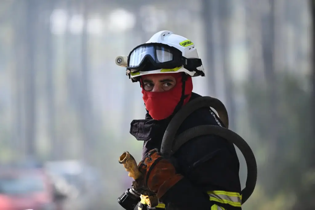 A firefighter carries his equipment as he works to suppress...