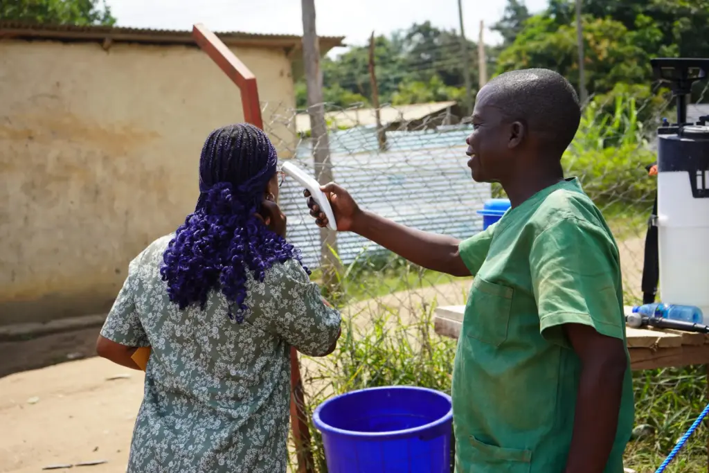 A health worker checks the temperature of a woman at the Ebola treatment center.