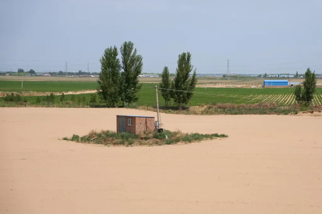 A shed is surrounded by a sandy plain near Ordos...