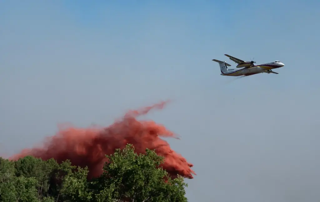 A water bomber drops water while fighting wildfires In Ares,...