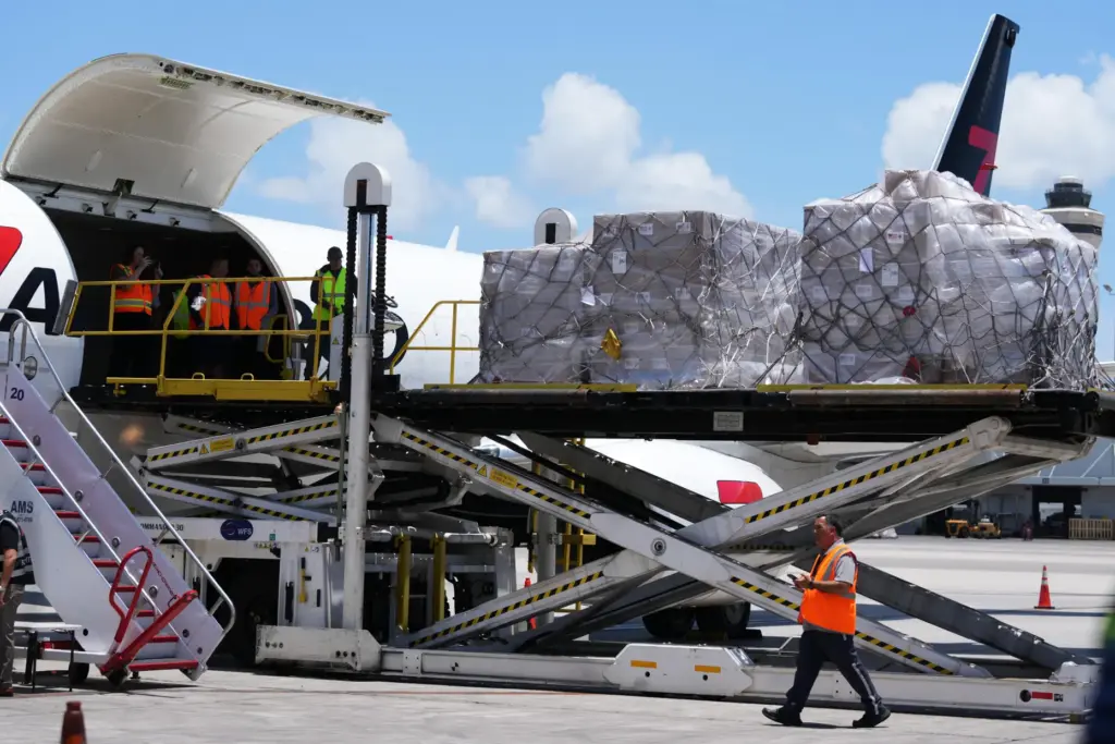 People load pallets containing food and hygiene kits for a...