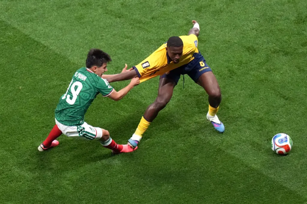 Mexico’s Gilberto Mora (19) challenges for the ball with Ecuador’s...