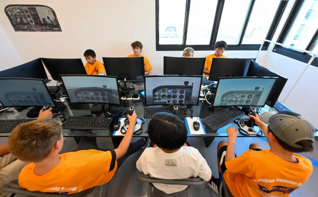 Campers fly a flight simulator during Aviation Summer Camp at...