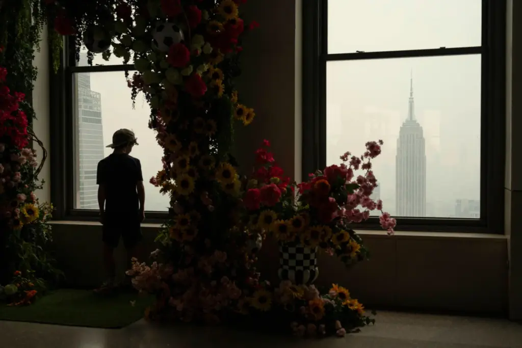 A person looks out a window at the Top of the Rock Observation Deck at wildfire smoke.