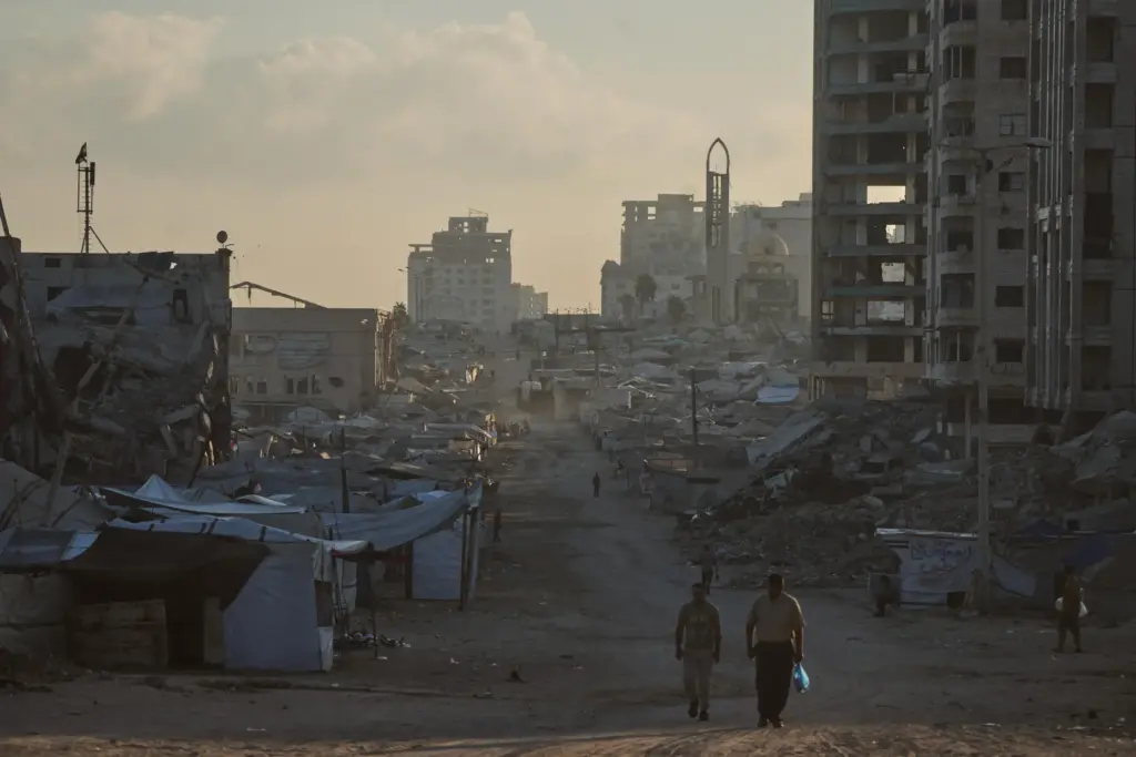 Palestinians walk along a street surrounded by buildings destroyed in...