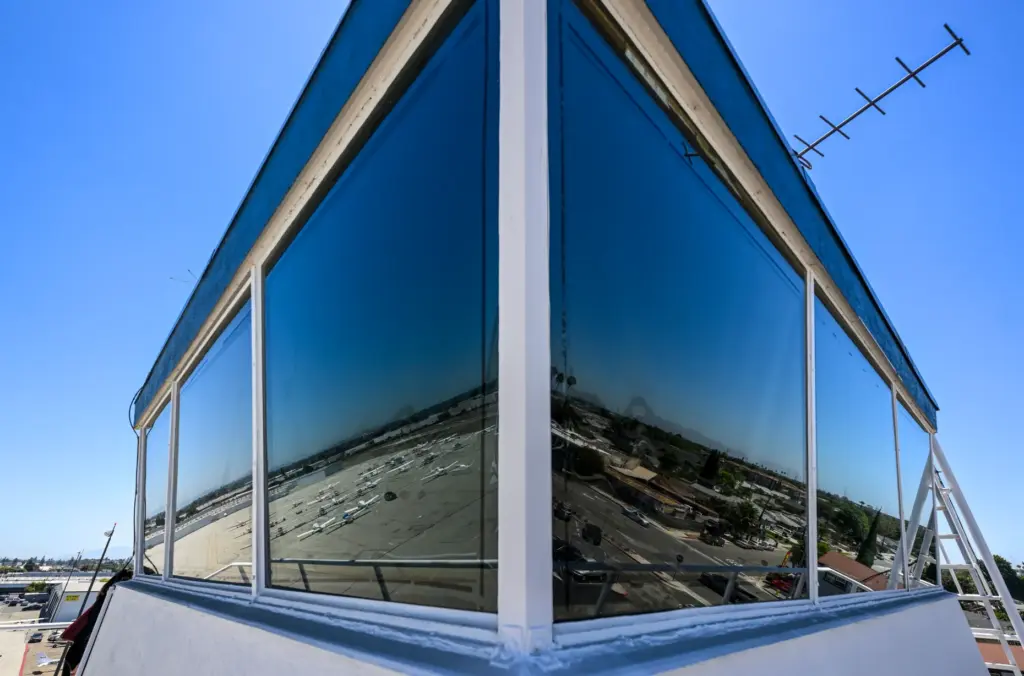 Parked aircraft are reflected in the window of the control...