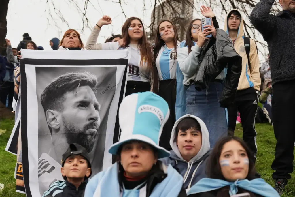 Argentina fans hold a photo of Lionel Messi as they...