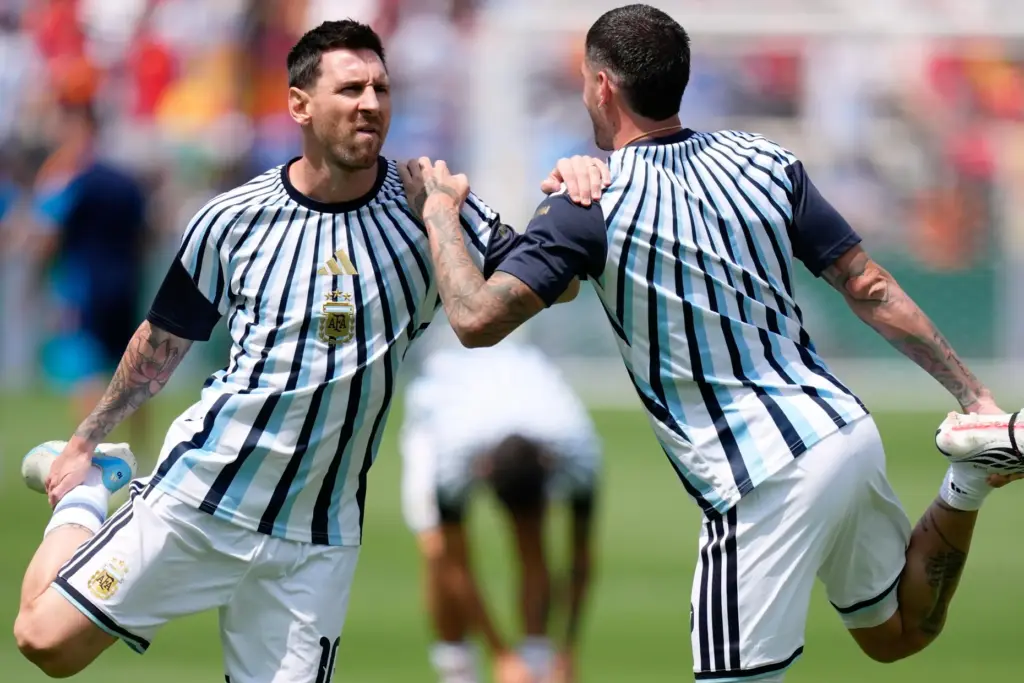 Argentina’s Lionel Messi stretches with teammate Rodrigo De Paul, right,...