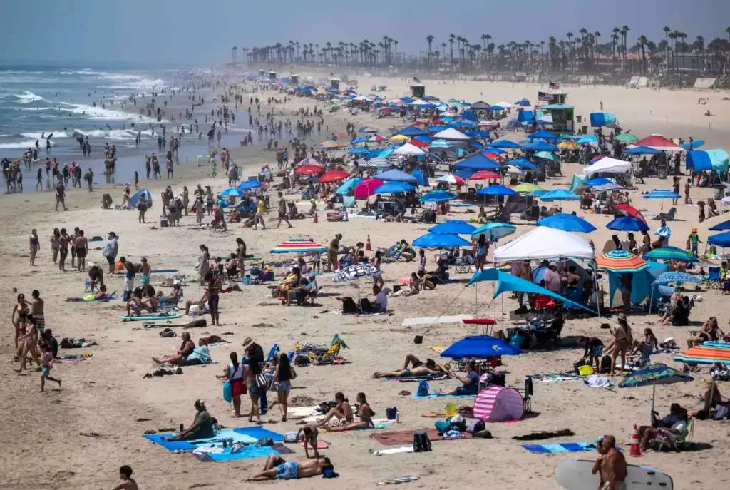 Thousands of beachgoers hang out on the sand and in...