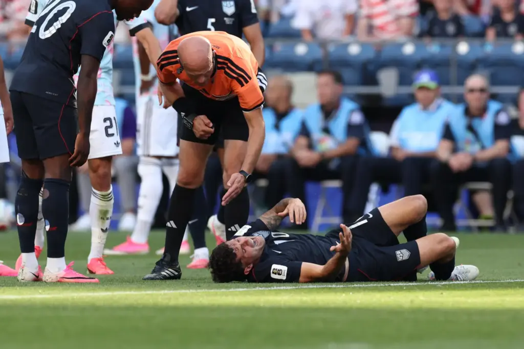 Referee Adham Makhadmeh, of Jordan, checks on Christian Pulisic.