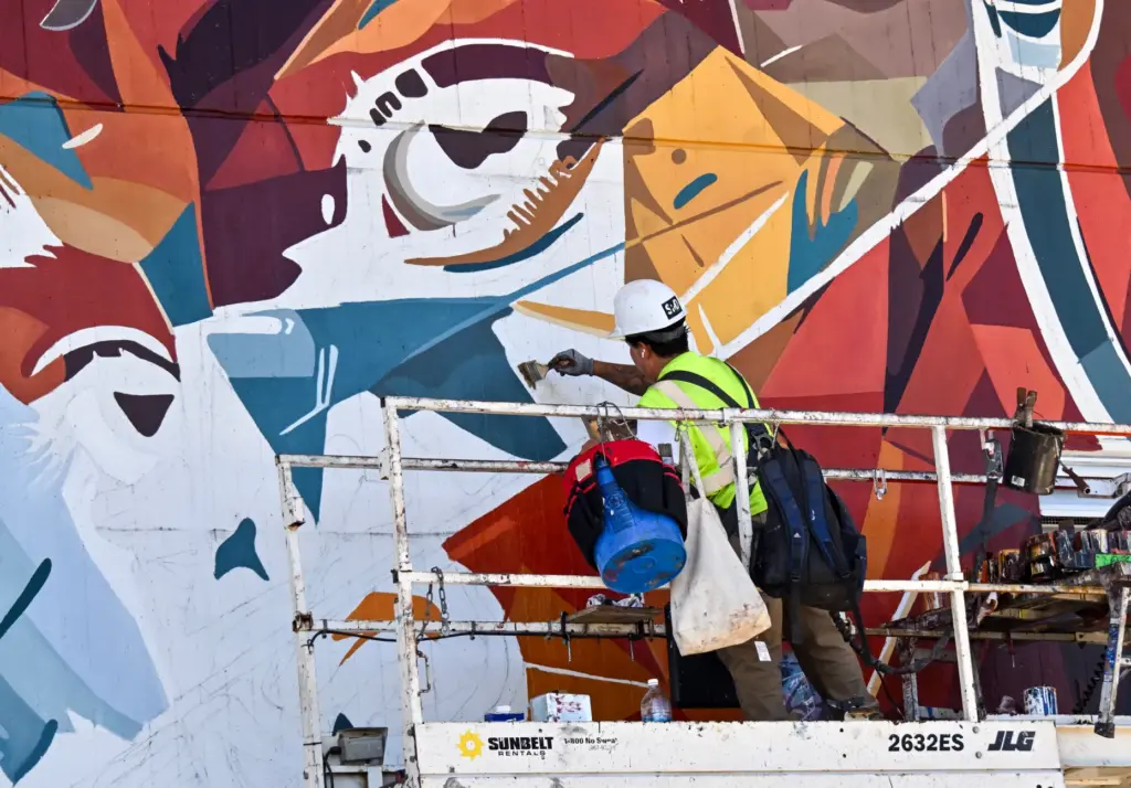 A worker installs Miami-based artist Brian Petersonâs mural at OC...