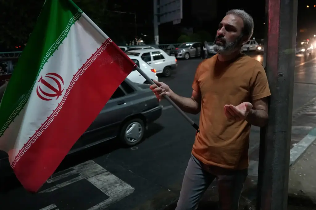 A demonstrator prays as he holds an Iranian flag in...