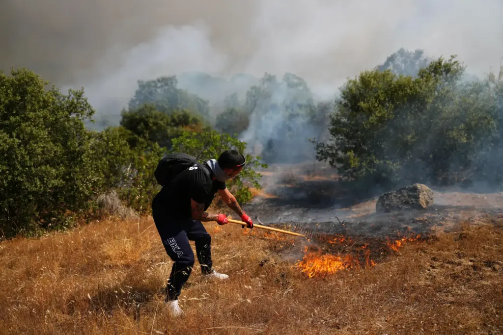 A volunteer uses a rake trying to help stop a wildfire from advancing in Spain.
