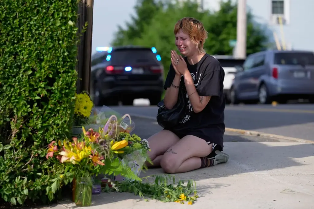 A woman prays after leaving flowers near the scene where...