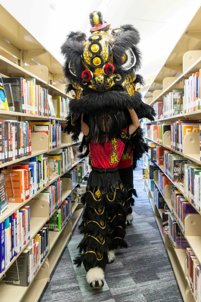 Lion dancers go through aisles of the library on Saturday,...