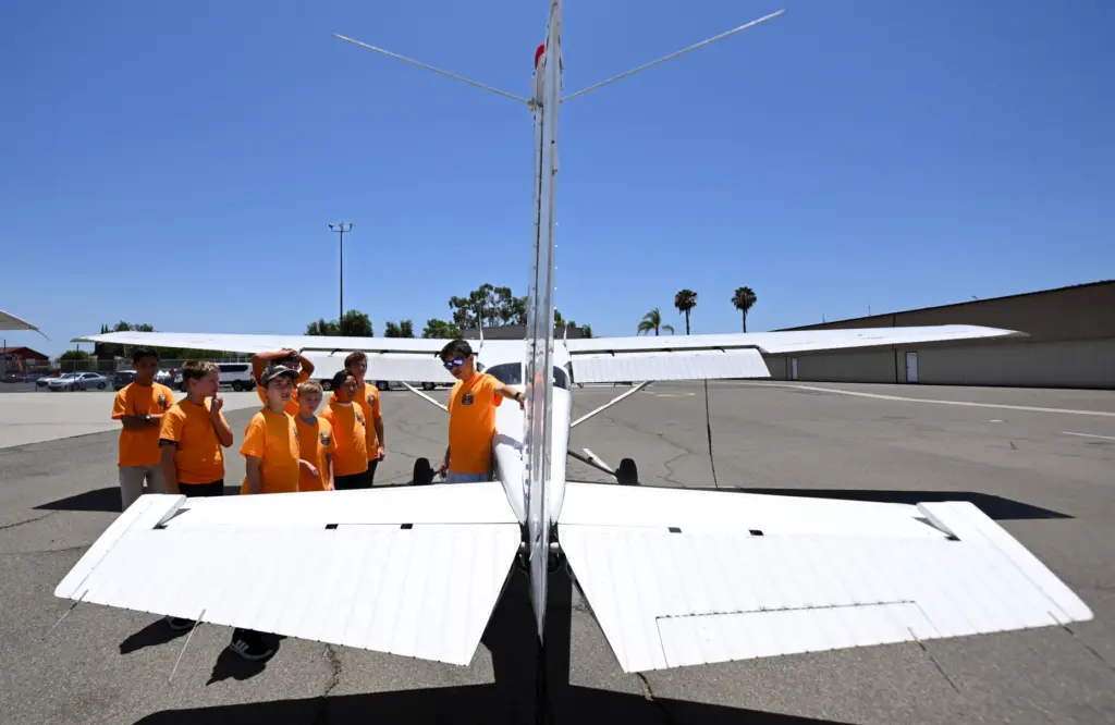 Counselor Baominh Dang shows campers how to preflight an Cessna...