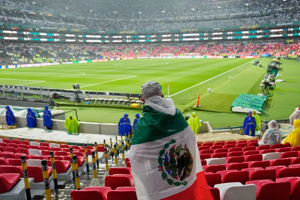 A Mexican fan waits in the rain for the start...