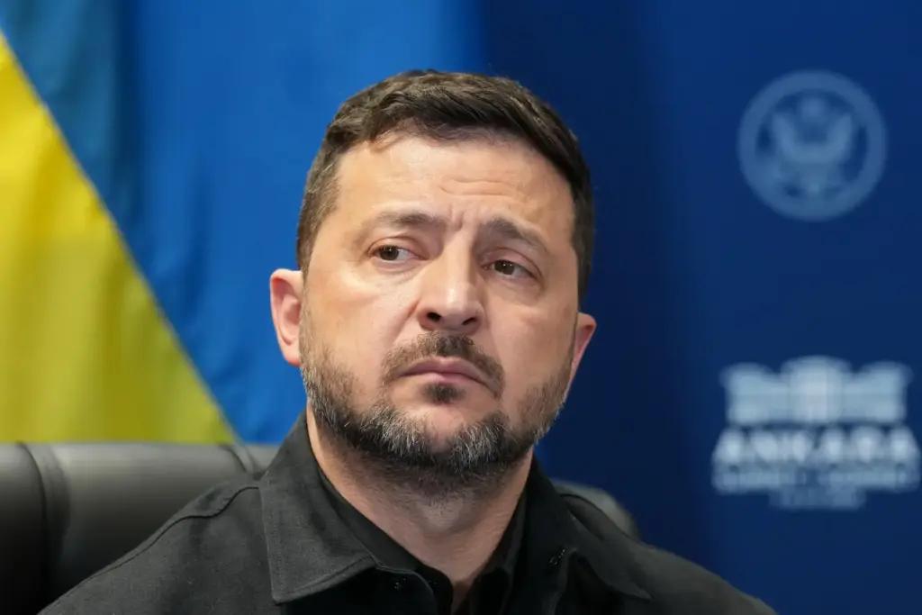 Ukraine's President Volodymyr Zelenskyy looks on.