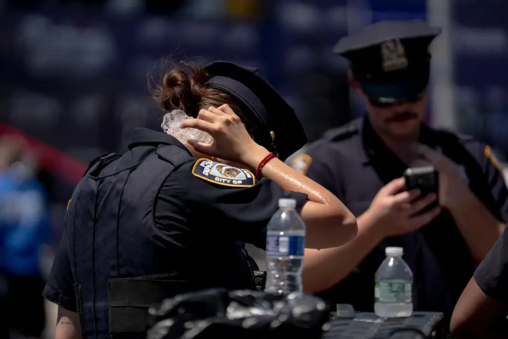 A police officer holds ice to their neck.