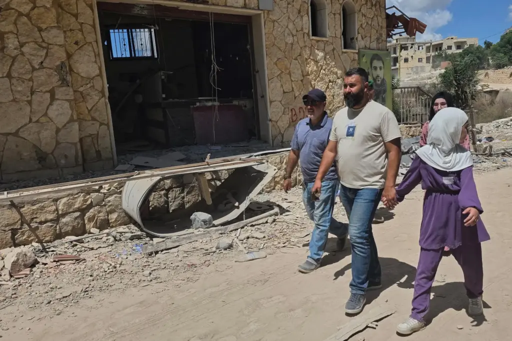 People walk through the village of Zawtar al-Gharbiyeh after the...