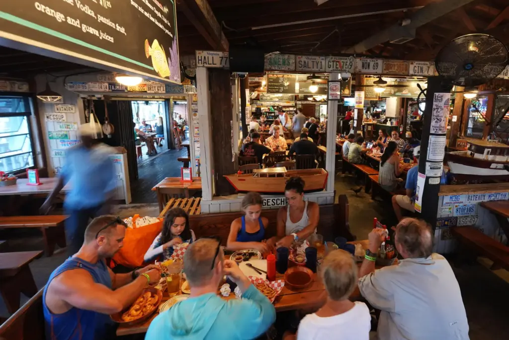An employee bussing tables, left, walks past diners as he...