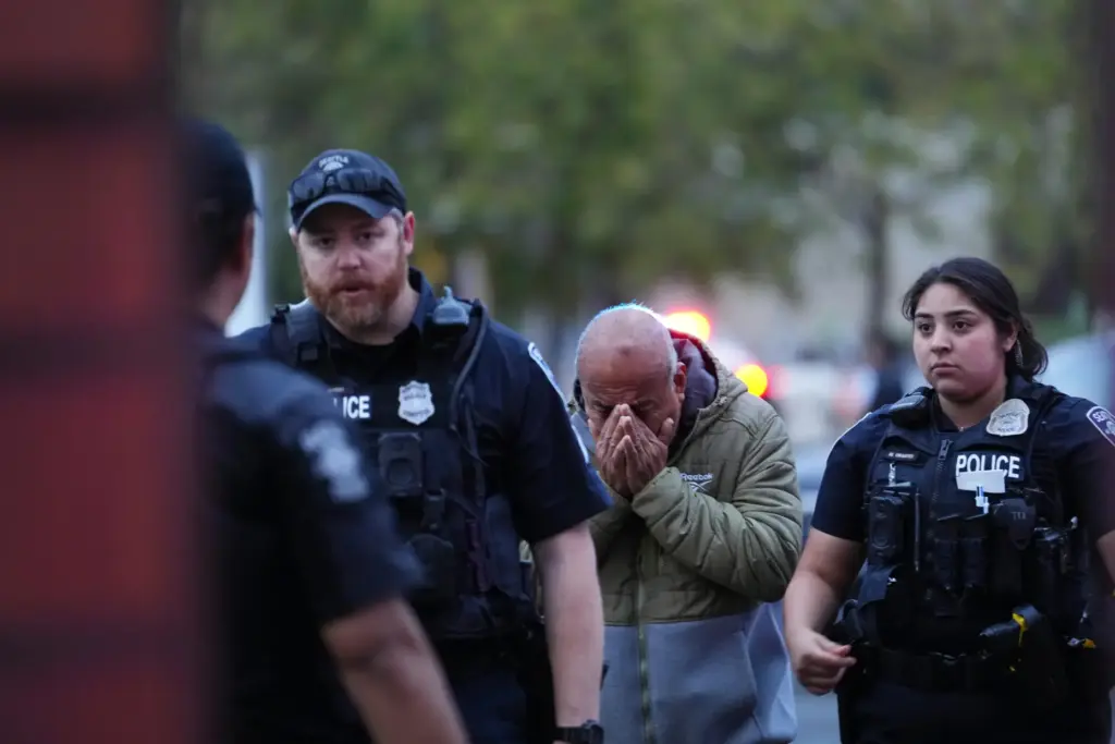 An unidentified man is led into the scene by police.