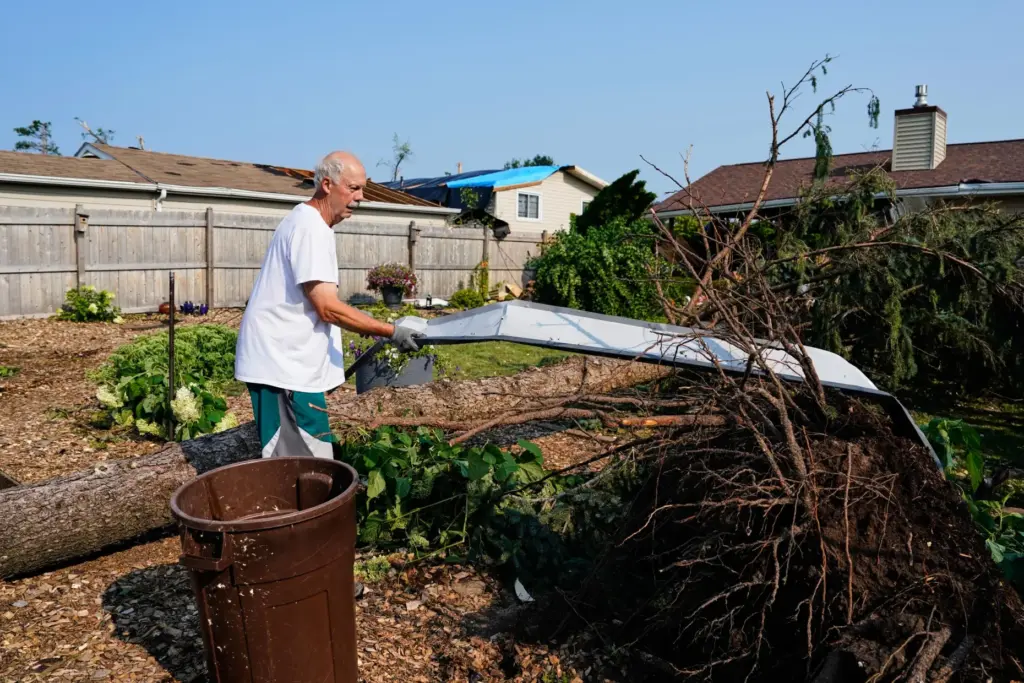 Williams Burrows cleans up debris in his backyard after a...
