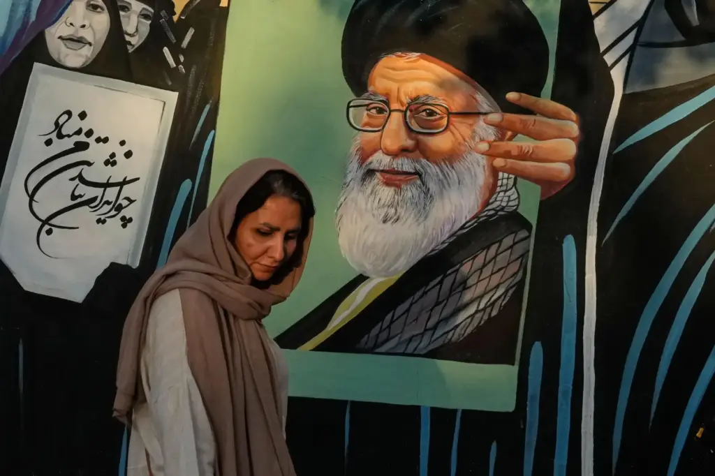 A woman walks past a mural depicting a portrait of...